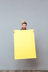 Wall Mural - Handsome young bearded birthday man holding copyspace board jumping