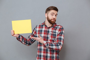 Wall Mural - Attractive young bearded man holding copyspace blank