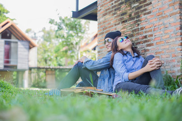 Poster - Hipster man playing guitar for his girlfriend outdoor against br