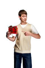 Cute young guy shows a finger on a beautifully wrapped gift. Man ready for Valentine's Day, to the Women's Day to Mother's Day. Boy holding a festive holiday gift.