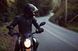 © Julian Walter - Male astride motorbike on road, looking over shoulder