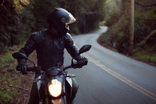 Male Astride Motorbike On Road, Looking Over Shoulder 