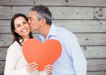 Canvas Print - Mature man kissing a woman holding red heart