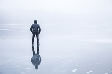 Man In The Mist Walking On The Lake Ice In Winter Afternoon. Peaceful Atmosphere. Foggy Air.