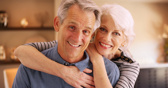 Wall Mural -  - Happy elderly couple sitting at home smiling at camera