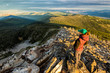 A female hiker stands atop a Montana peak at sunset