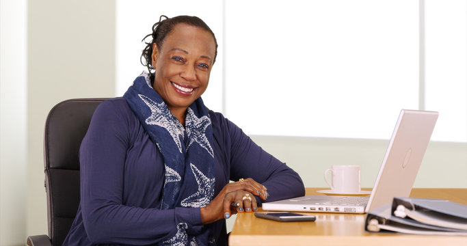 Wall Mural -  - A black businesswoman poses for a portrait at her desk