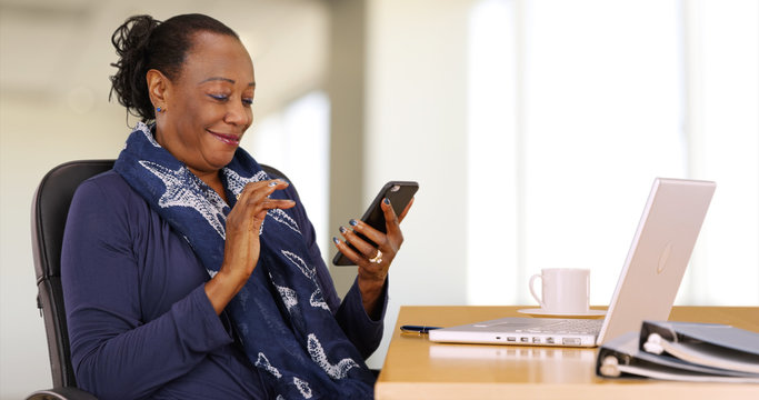 Wall Mural -  - An African American businesswoman uses her mobile phone at her desk