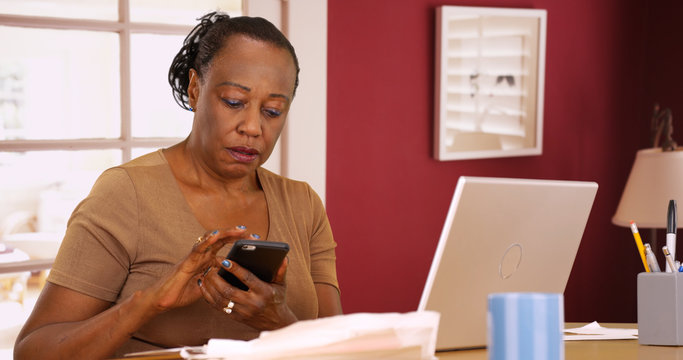 Wall Mural -  - An older black woman uses her phone and laptop to do her taxes