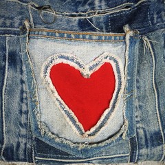 decorative red heart and ripped denim pocket on white lace background. destroyed torn denim blue jea