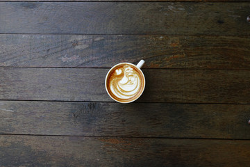 cup of latte art coffee on wooden background