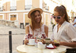 © Monkey Business - Two female friends reading a guidebook outside a cafe, Ibiza