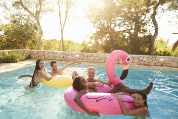 Group Of Friends On Vacation Relaxing In Outdoor Pool