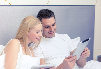 Canvas Print - smiling couple in bed with tablet pc computers