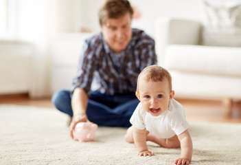 happy father with baby and piggy bank at home