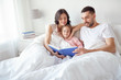 © Syda Productions - happy family reading book in bed at home