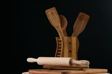 Set of the wooden kitchen utensils on black background. spoon, kitchen spatula, rolling pin, fork, closeup