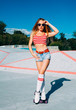 Beautiful blonde girl posing on a vintage roller skates in denim shorts and white, red T-shirt in the skate park on a warm summer evening. Rollers quads derby.