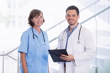 Canvas Print - Nurse and doctor discussing over clipboard in corridor