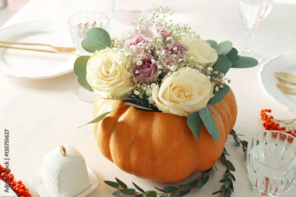Beautiful composition of fresh flowers and pumpkin on white table