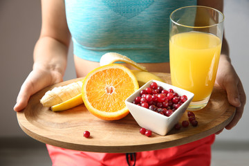 Wall Mural - Closeup of sporty woman holding wooden tray with healthy breakfast