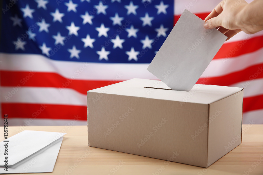 Hand inserting envelope in ballot box on USA national flag background