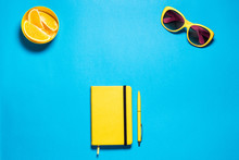Stylish Minimalistic Feminine Fashion Workspace. Bright Yellow Glasses And Diary With Pen, Pirces Oranges Against Deep Blue Copy Space. Top View.