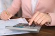 © Africa Studio - Woman sitting at table with calculator, document and pen