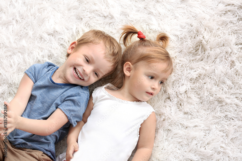 Cute funny children lying on carpet at home