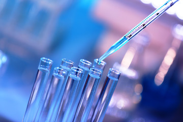 Pipette dropping a sample into a test tube, closeup