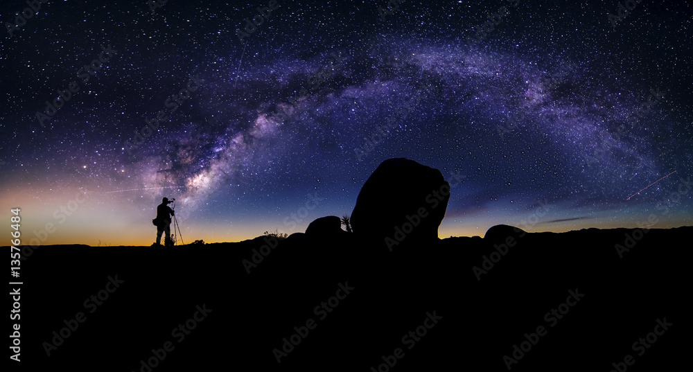 Photographer doing astro photography in a desert nightscape with milky way galaxy.  The background is stary celestial bodies in astronomy.  The heaven depicts science and the divine. - obrazy, fototapety, plakaty 