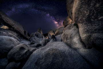 photographer doing astro photography in a desert nightscape with milky way galaxy. the background is