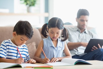 Canvas Print - Attentive siblings doing homework in living room