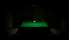 Snooker In The Dark. Billiards In The Center Under Lamp Light In The Darkness. Pills Balls And Lamp. Empty Billiard Room