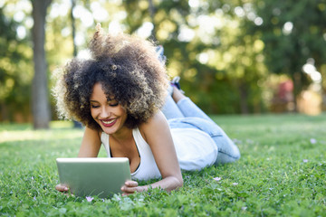 Canvas Print - Mixed woman with afro hairstyle looking at her tablet computer