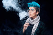 hipster woman with blue hair smoking vape on black background