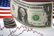 Concept Of Oil Stock Market Exchange Trading. Lines Of Oil Prices On The Chart. One Us Dollar Bill Standing On The Prices Diagram. Heap Of Quarter Dollar Cents Near One Dollar Bill. US Flag.