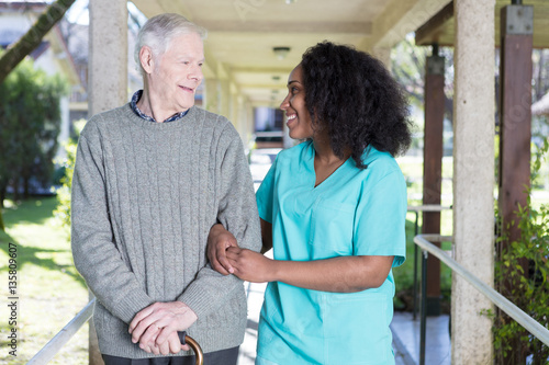Fotografie, Obraz African nurse assisting elderly man outdoor