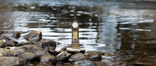 Model Standing Clock Stands On A Pebble By The Waterside