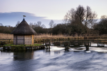 Beautiful landscape on frosty Winter morning of eel traps over f