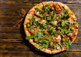 Wall Mural - High angle view of pizza with arugula olives on wooden table