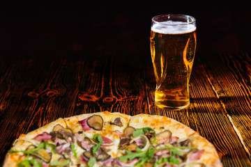 Wall Mural - Pizza with ham on wooden table near a glass of beer