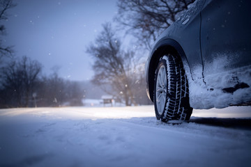 Car and falling snow in winter on forest road.