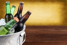 Closeup Of A Metal Ice Bucket Filled With Assorted Beer Bottles. Horizontal Format With Copy Space And Warm Background.
