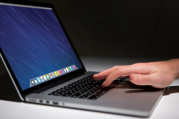 Hand typing on a keyboard of laptop with operating system screen on background