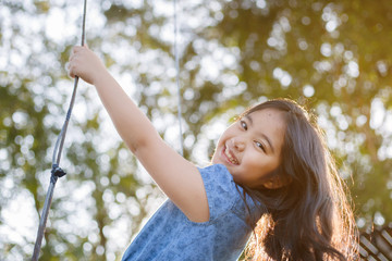 Wall Mural - Happy little Asian girl playing swing outdoor in the park