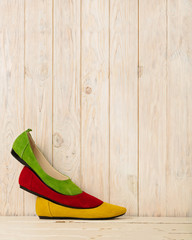 Red, green and yellow women's shoes (ballerinas) on wooden backg