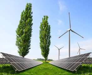 Solar panels with wind turbines on meadow. Power plant using renewable energy.