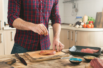 man cooking grilled steak on the home kitchen