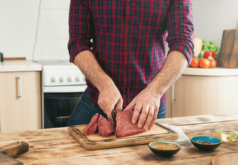 Wall Mural - Man cooking beef meat on wooden table in the kitchen